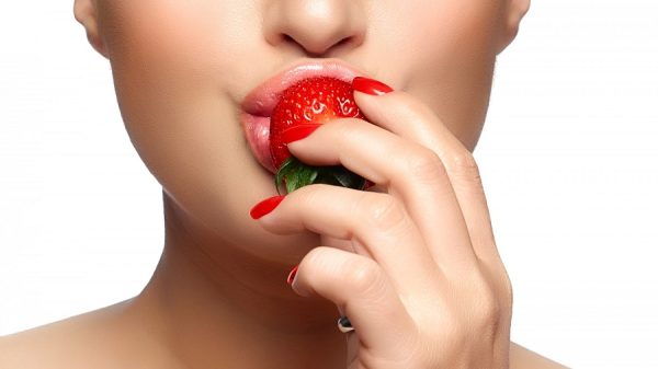 close-up of a woman’s lips with her finger touching them