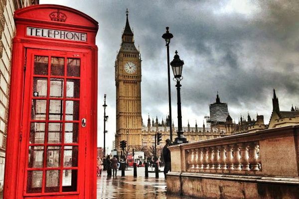 elegant woman walking through london street with red telephone booth in background