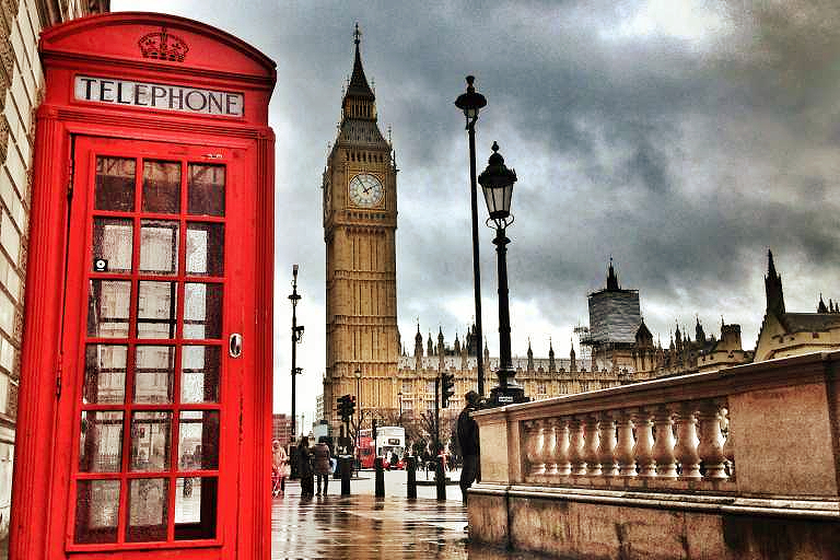 elegant woman walking through london street with red telephone booth in background