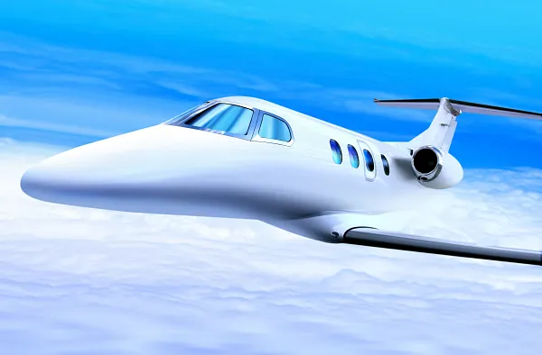 Luxury private jet flying above the clouds under a clear blue sky