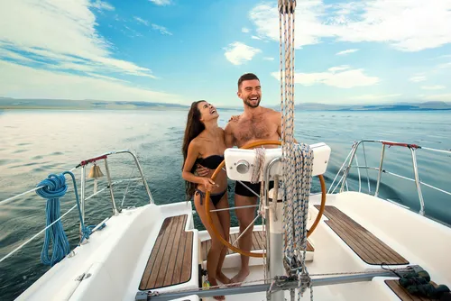Elegant couple enjoying a luxury yacht cruise on calm blue waters during an exclusive travel experience