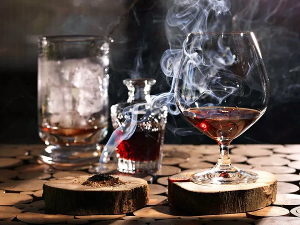 Premium-Whiskey-and-Cigar-Lounge-Experience Glass of whiskey with cigar smoke, crystal decanter, and ice in a sophisticated lounge setting