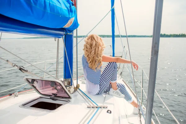 Elegant woman relaxing on a luxury yacht while enjoying scenic waterfront views during a premium travel experience