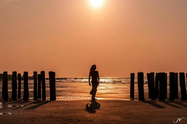 woman in dress standing near sea at sunset
