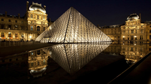 paris louvre pyramid reflected in water at night