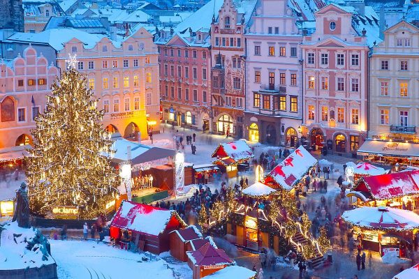couple wrapped in coats strolling through decorated christmas market square