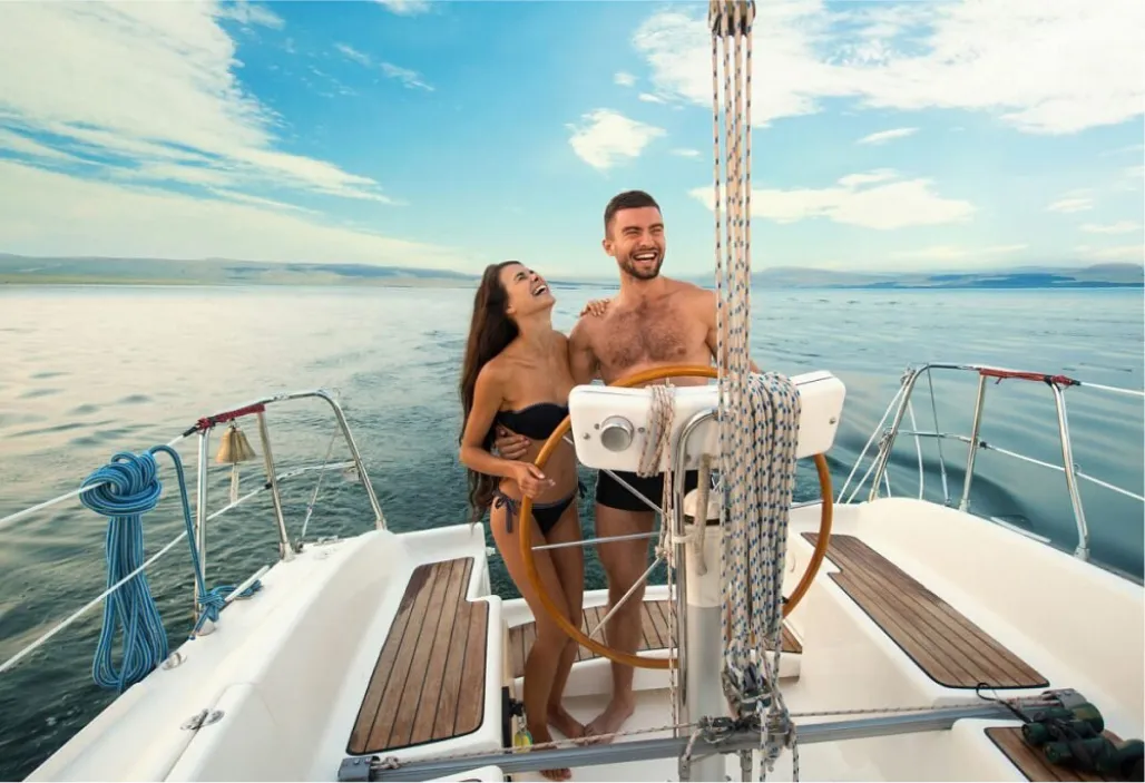 man and woman laughing while lounging on a yacht in turquoise waters