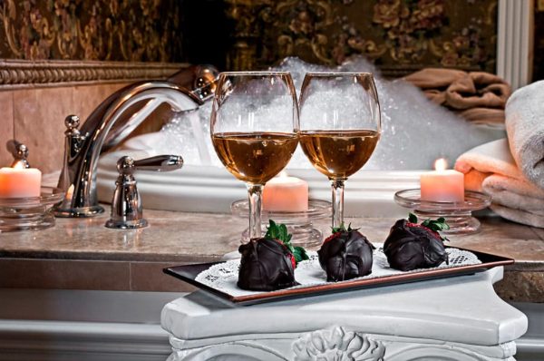 cozy hotel room with rose petals and champagne on the bed