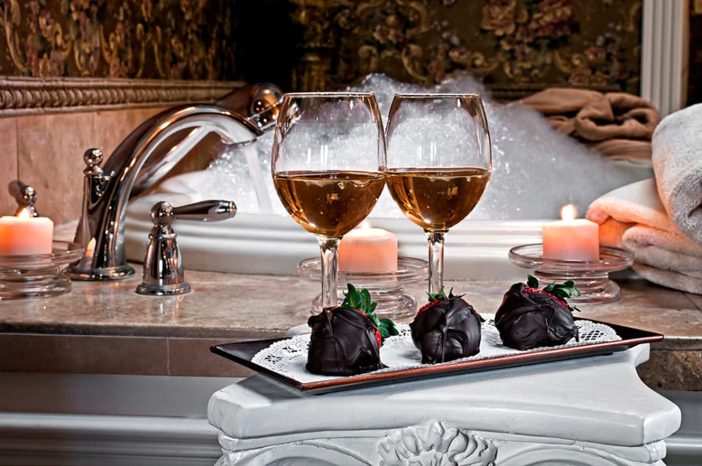 cozy hotel room with rose petals and champagne on the bed
