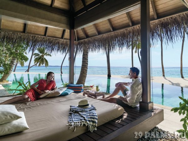 woman in swimsuit enjoying drink in beachside cabana with ocean view