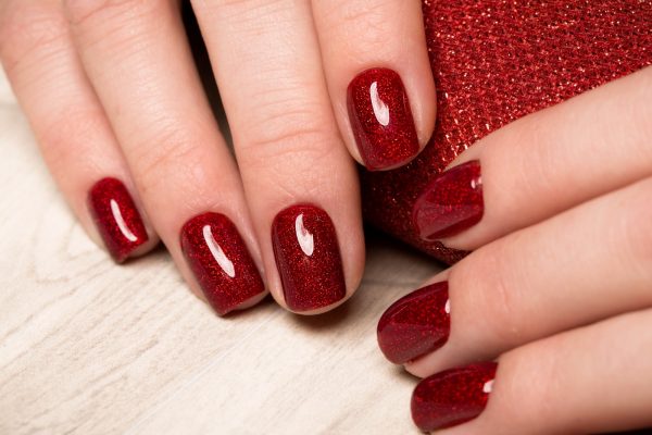 Woman’s hand with red manicure — symbolizing elite millionaire dating lifestyle