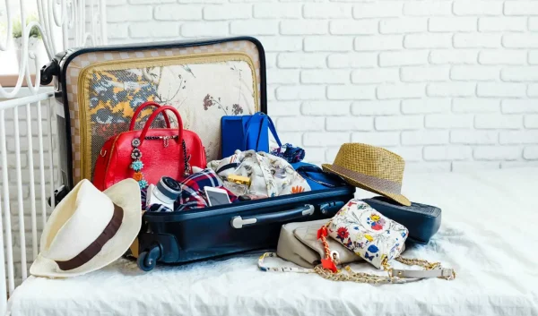 Open suitcase with clothes, hats and bags ready for a stylish trip across Europe with a travel companion