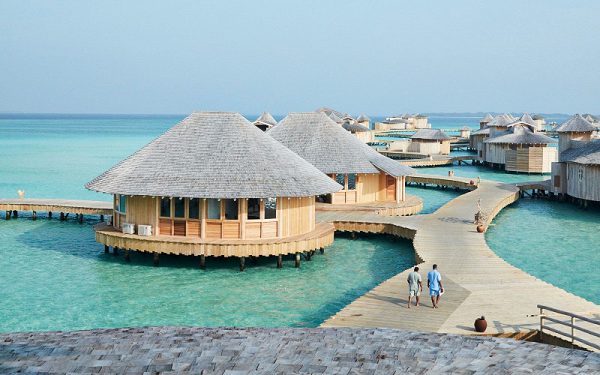 Woman in pink bikini arriving on white sand beach — elite travel companion in the Maldives